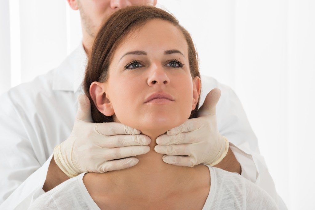 doctor checking thyroid of patient