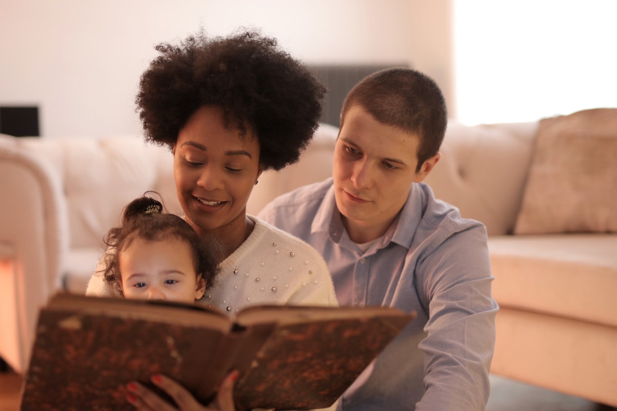 parents reading book to toddler