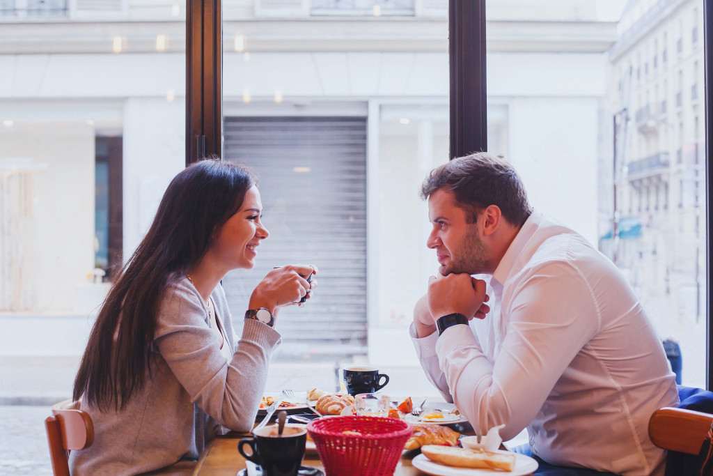 a man and woman at a restaurant talking and smiling